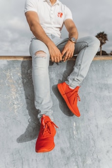 man wearing white polo shirt and pair of red sneakers