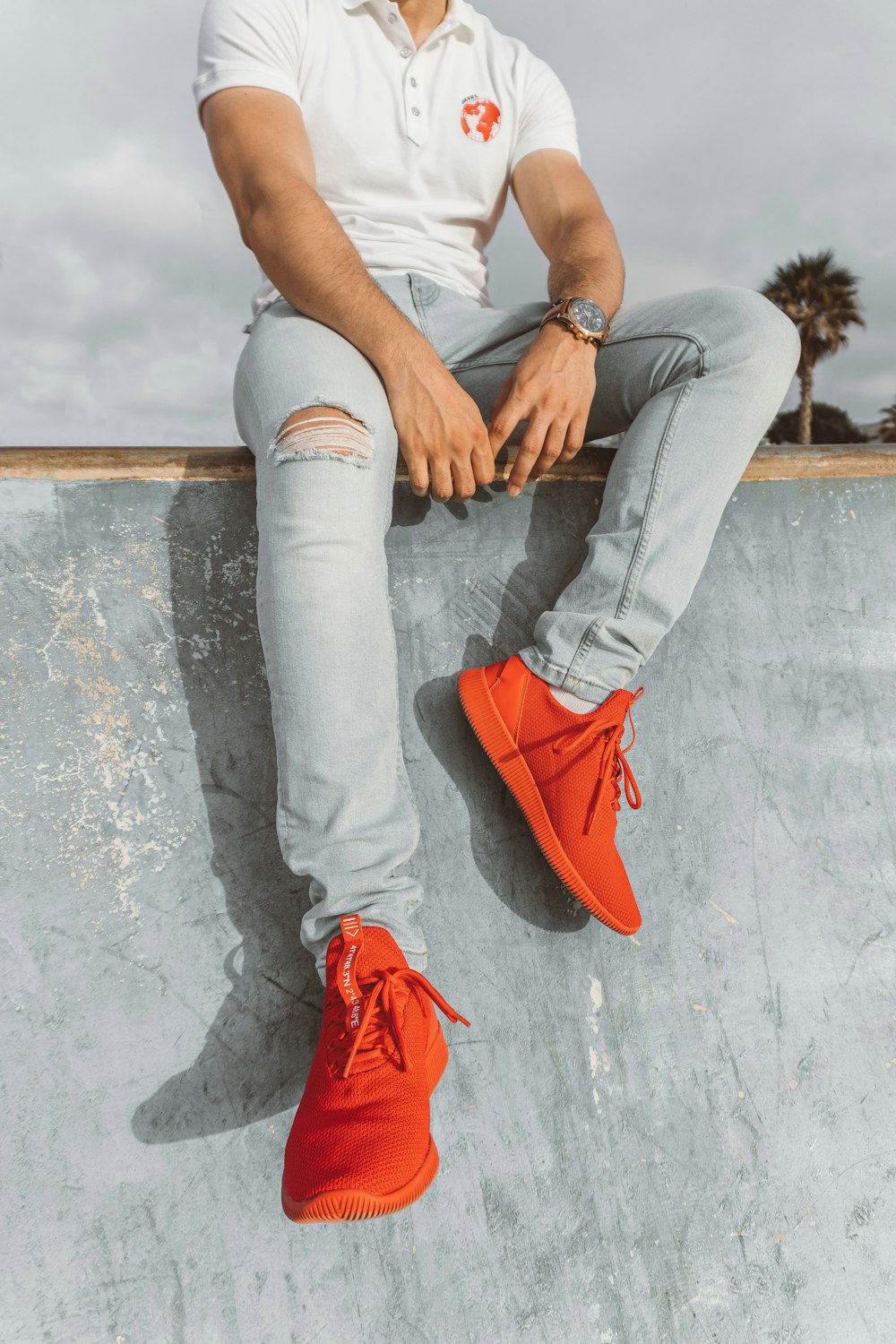 man wearing white polo shirt and pair of red sneakers