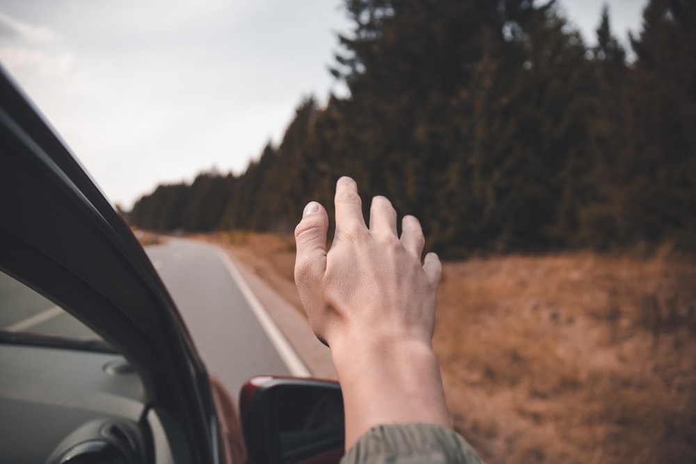 selective focus photography of person's hand hear car wing mirror