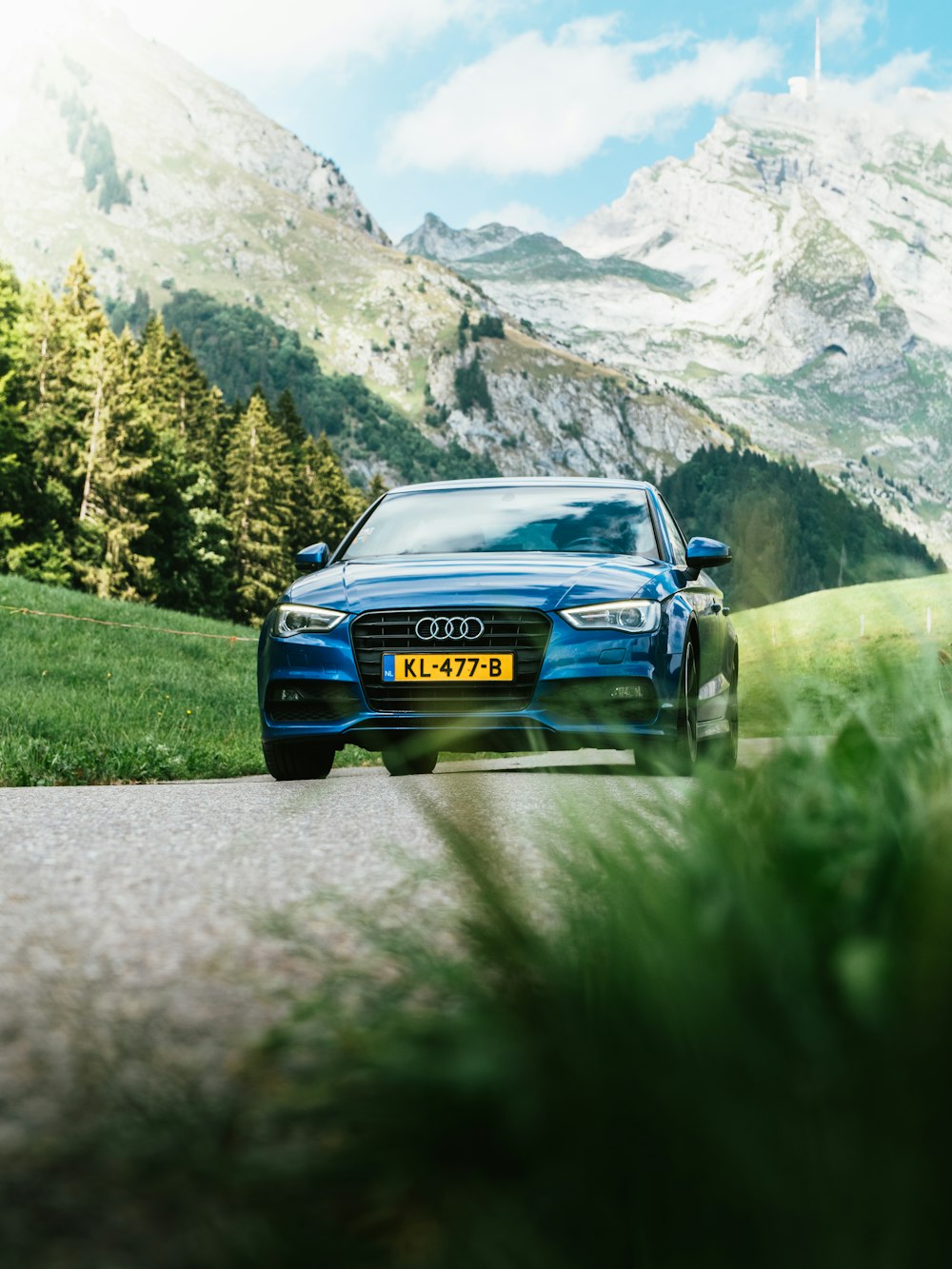 blue Audi vehicle traveling on road