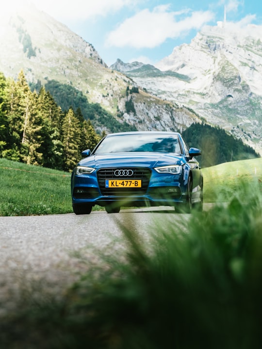 blue Audi vehicle traveling on road in Swiss Alps Switzerland
