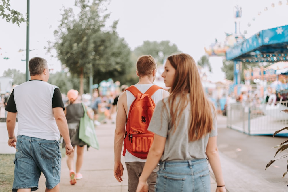 woman walking near two men in pathway during daytime