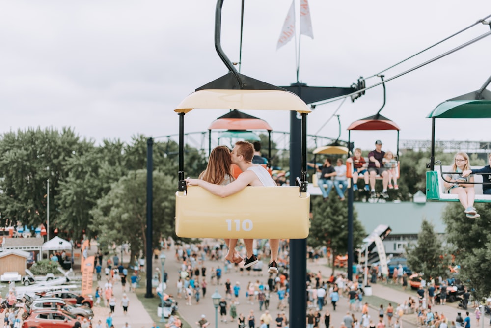 man kissing woman while riding on cable car at daytime