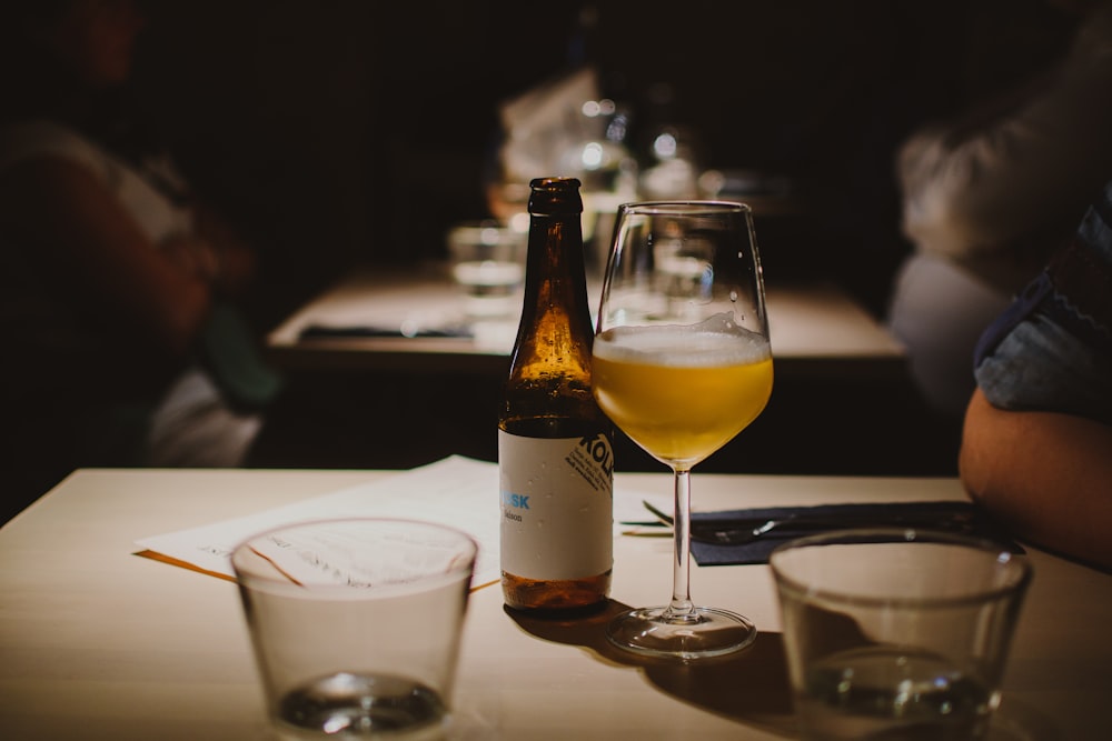 beer bottle beside wine glass on table