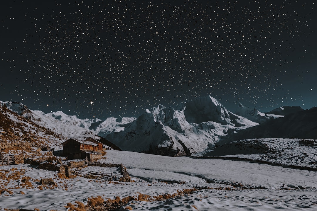 snow covered mountains under dark sky