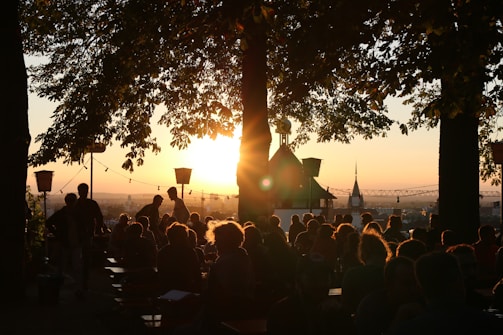 A vibrant community gathering worshipping together outdoors at sunset.