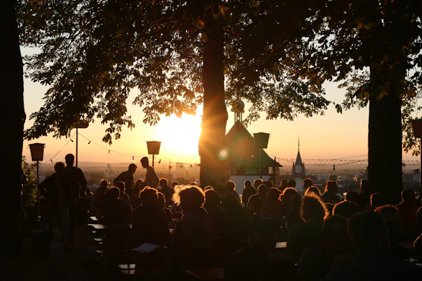 A vibrant community gathering worship music outdoors at sunset.