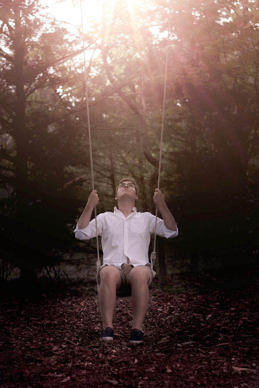 man in white dress shirt sitting on swing