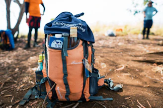 A sturdy black backpack with neon orange survival gear neatly arranged.