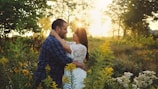 A couple embracing in a sunlit field during their prenup photo session.