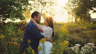 A couple embracing tenderly in a sunlit field during their pre-wedding shoot, with soft golden hour light.