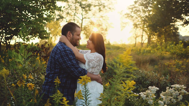 A couple embracing tenderly in a sunlit field during their pre-wedding shoot, with soft golden hour light.