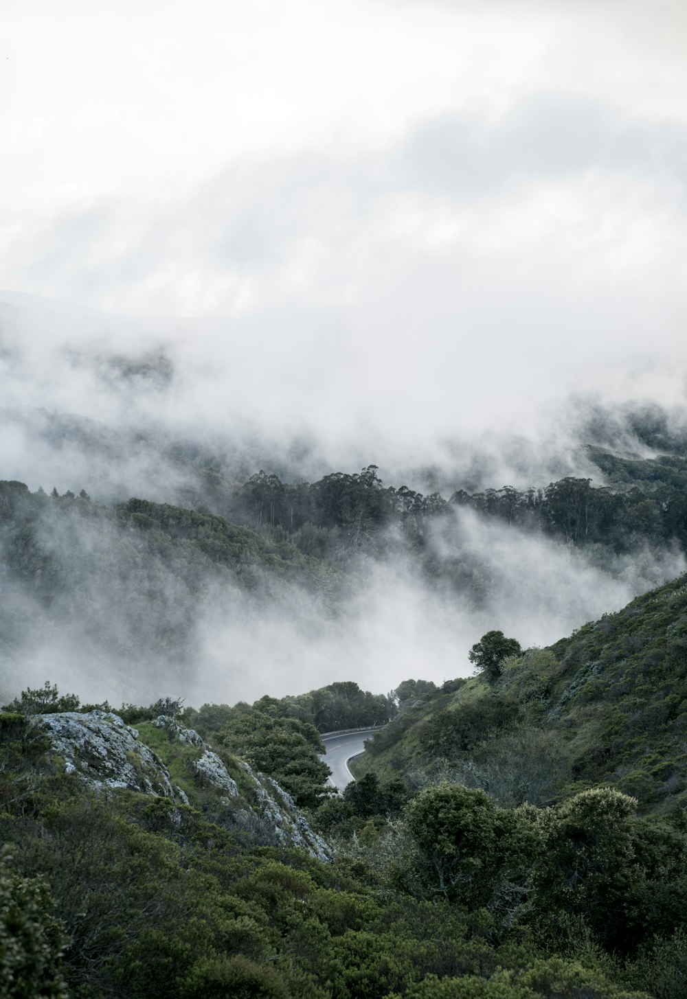 body of water between mountain under foggy sky