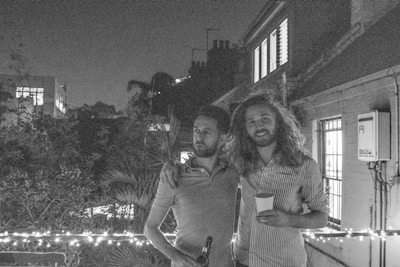 Two people laughing together on a glassy balcony with soft shadows.