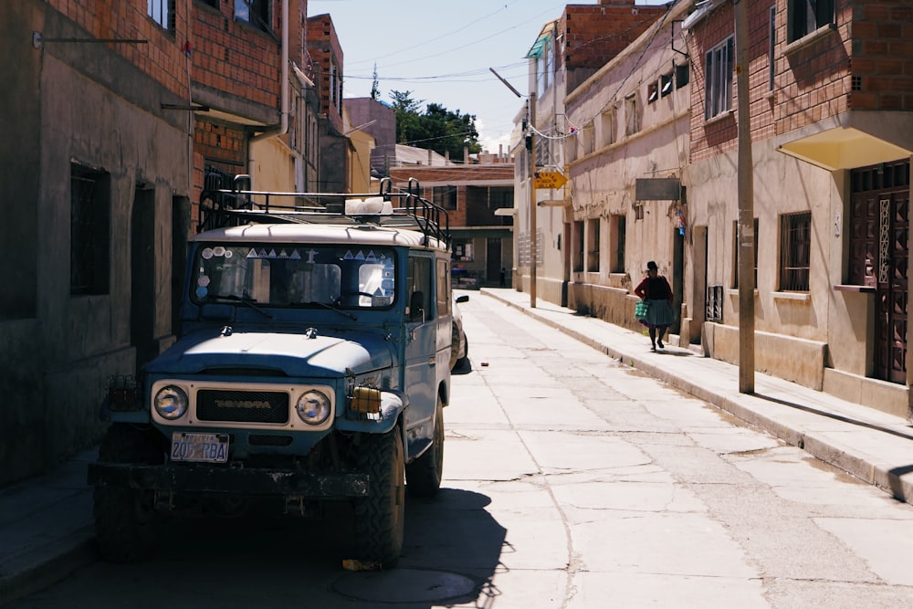 blue off-road vehicle beside commercial buildings during daytime