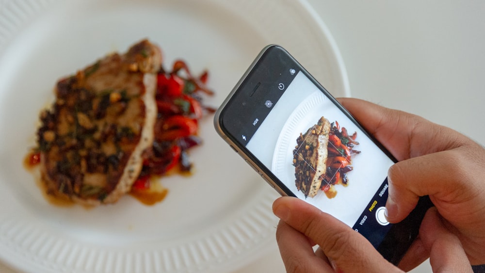 Person, die ein Foto von angerichtetem Essen macht