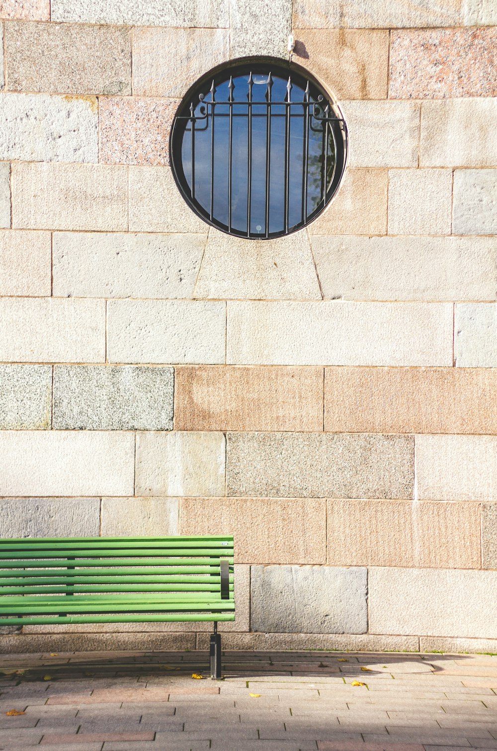 green slatted bench near brown wall