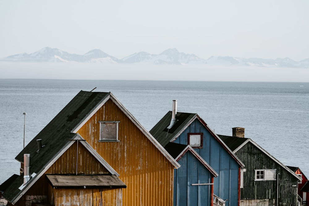 three orange, blue, and black wooden houses lined up in front of sea