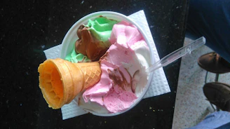 A colorful bowl of mixed fruit ice cream scoops with a wooden spoon