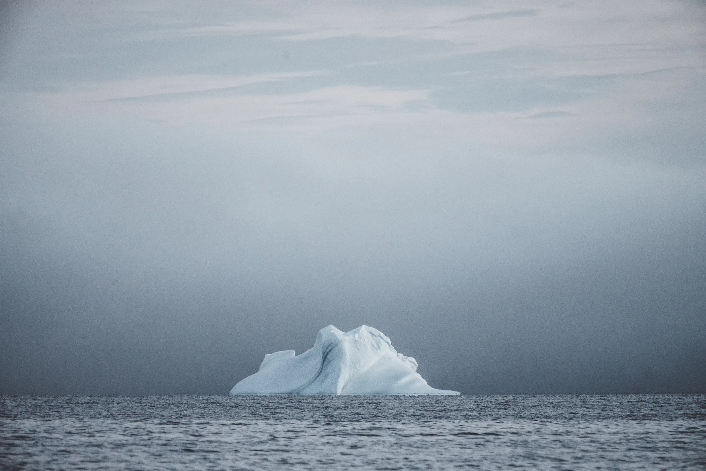 A single iceberg floating in still Arctic water off Greenland