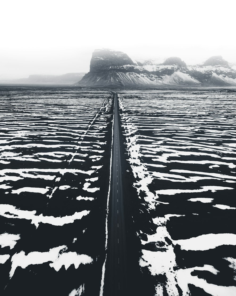 Foto en escala de grises de la montaña y el cuerpo de agua
