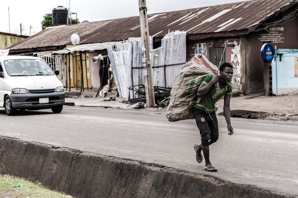 man holding brown sack beside pave road