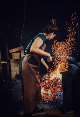 Artisan tending the glowing agave roasting pits with sparks flying.
