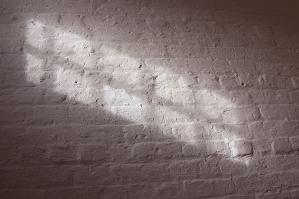 a white brick wall with a shadow of a person on it