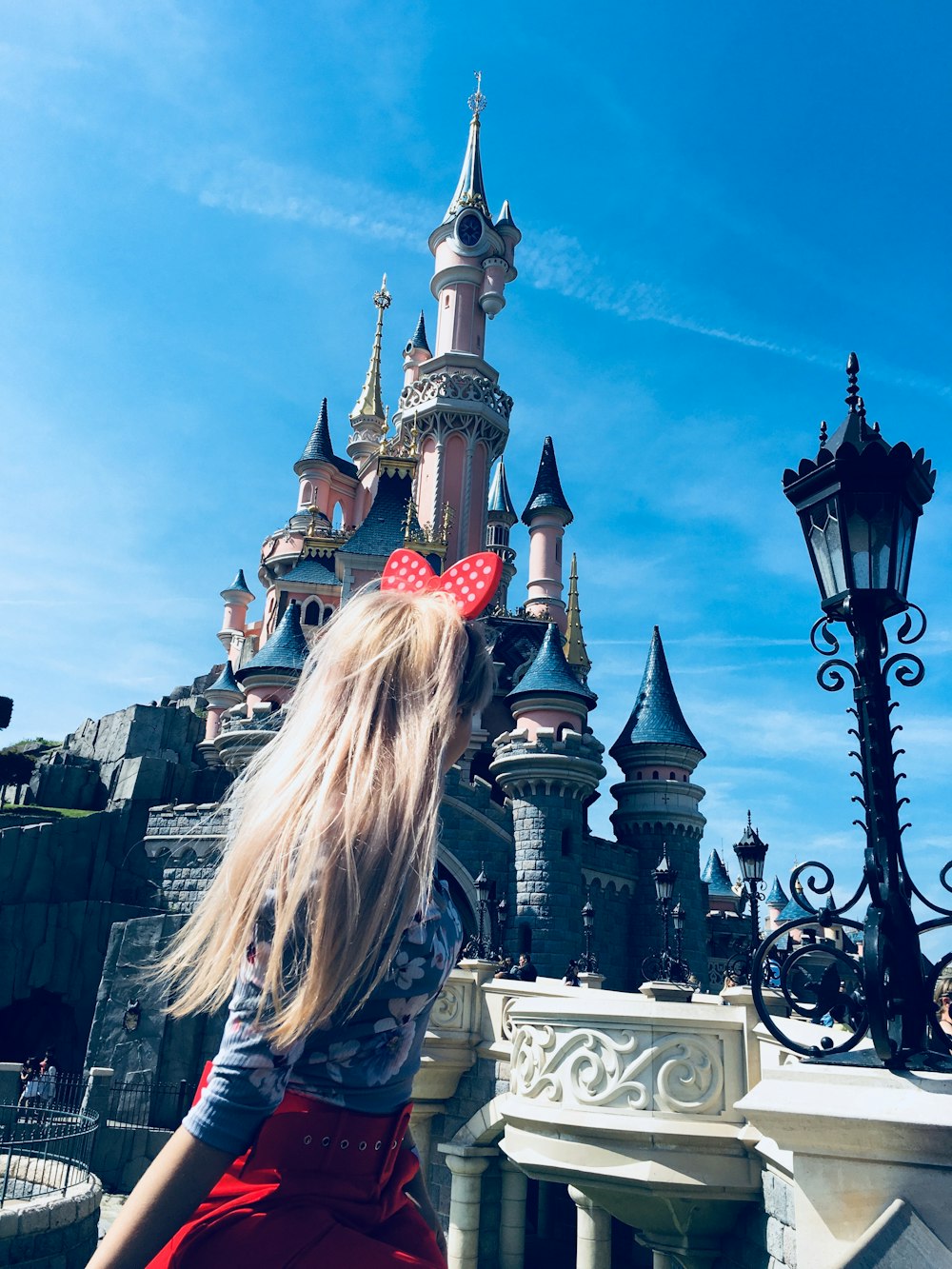 Menina vestindo a banda vermelha de Alice olhando para o castelo da cinderela