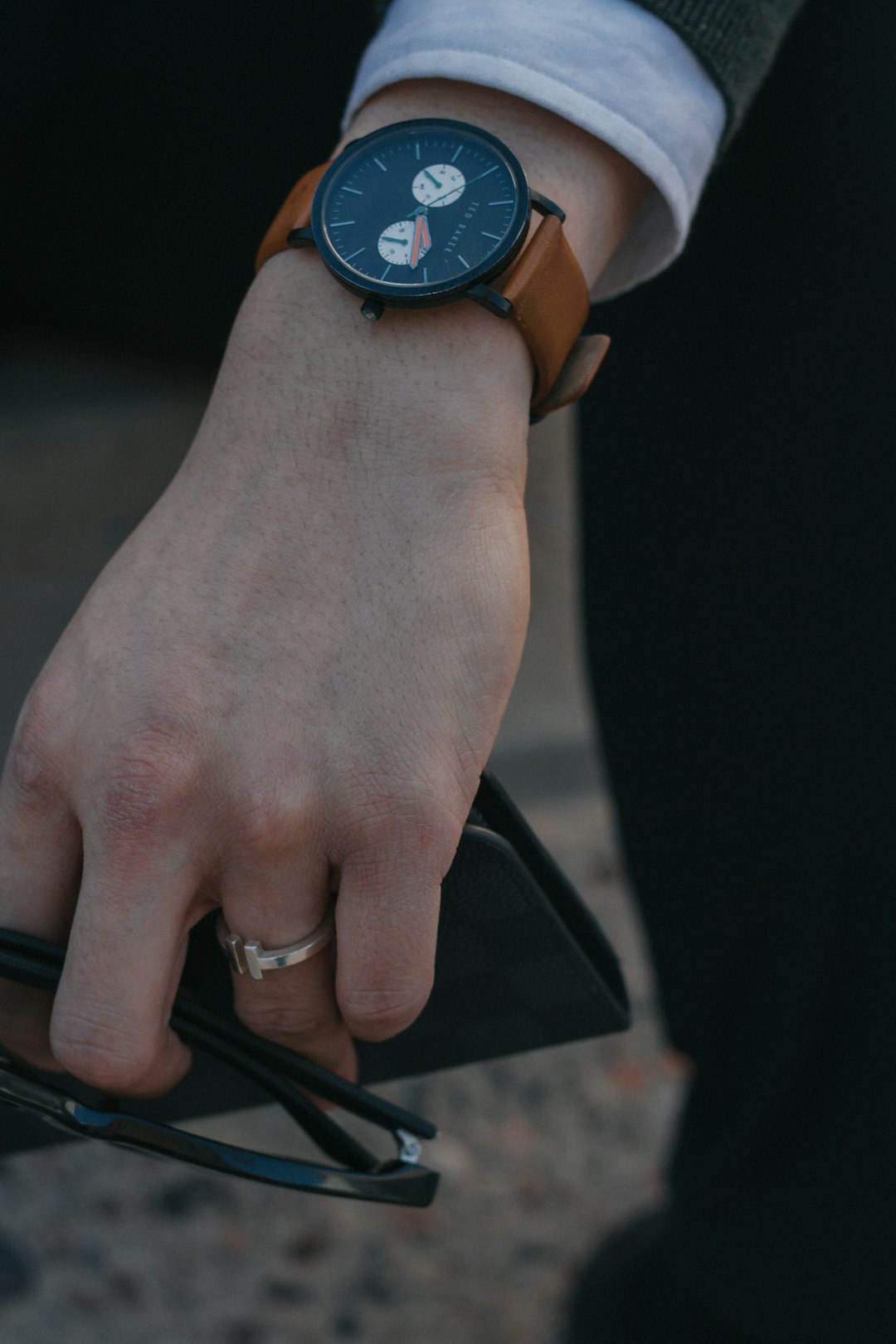 person holding sunglasses with black and brown watch