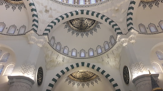 A serene mosque interior with soft natural light filtering through geometric patterned windows.