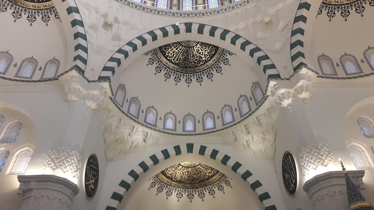 A peaceful mosque interior with intricate Islamic geometric patterns and calligraphy.