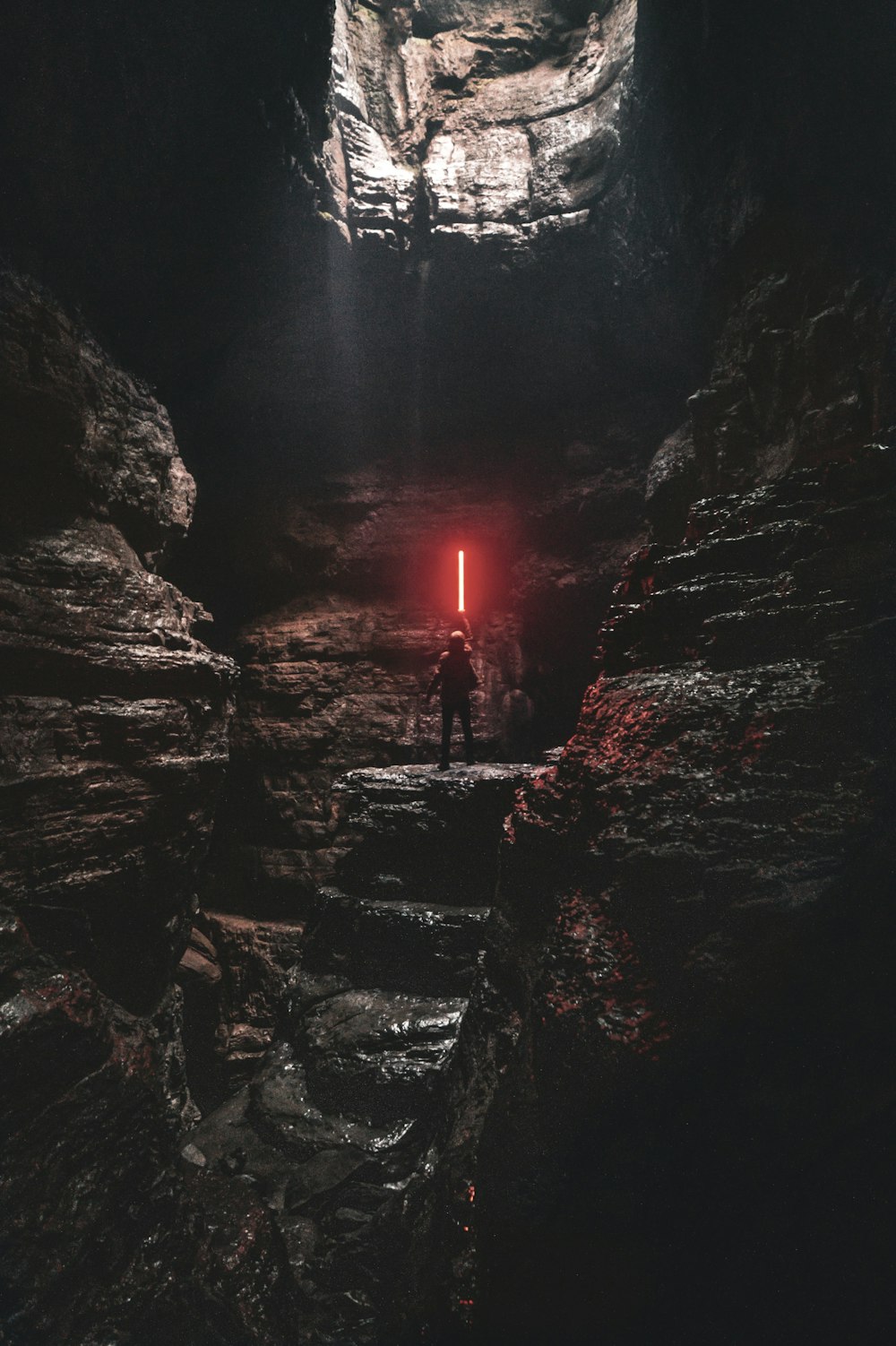 man holding red lightsaber standing on cliff