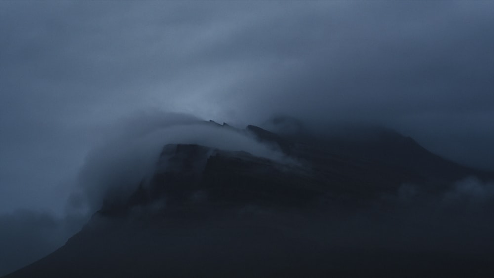 a large mountain covered in a cloud covered sky