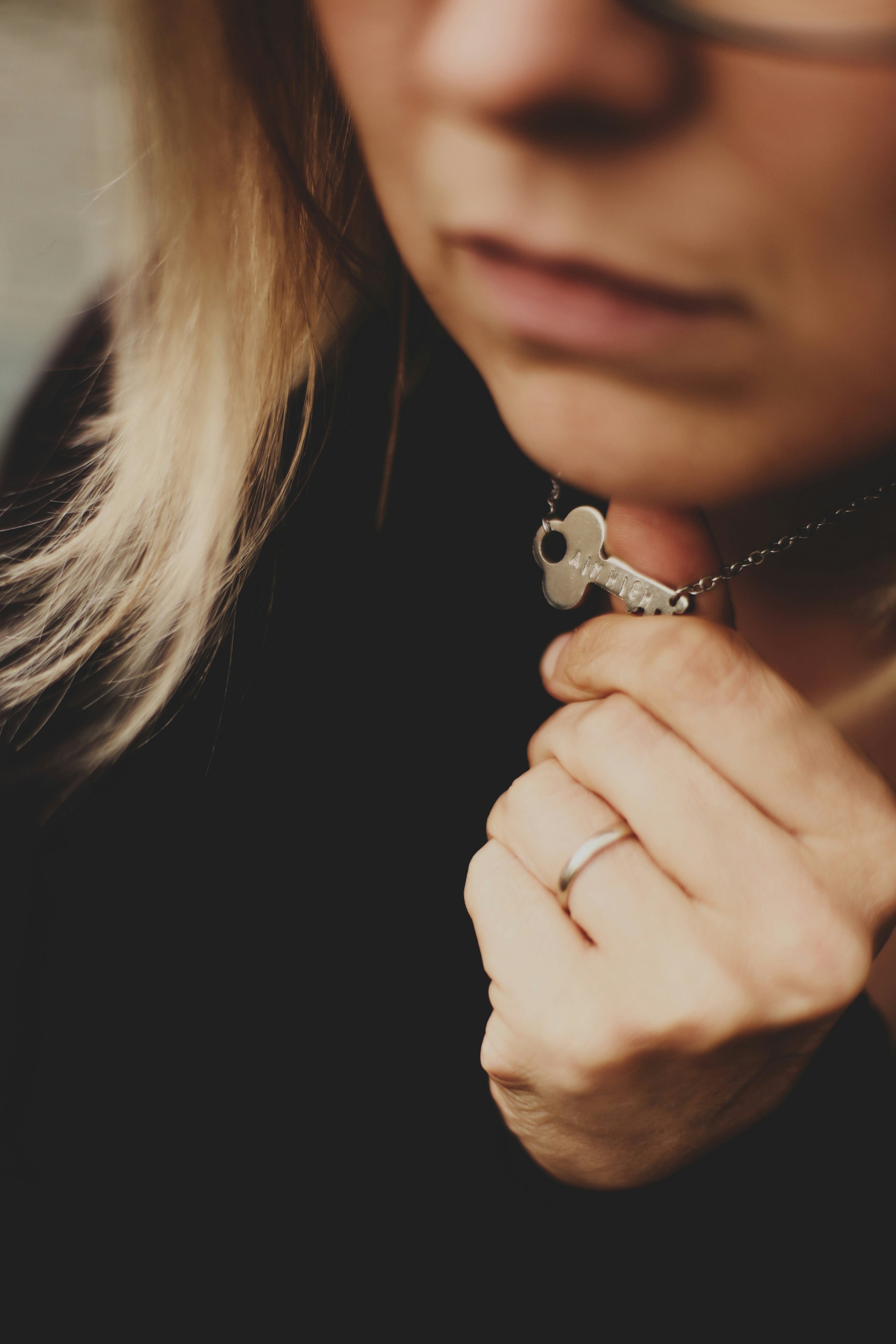 woman in black top holding silver-colored necklace
