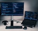 laptop computer beside monitor with keyboard and mouse