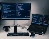 laptop computer beside monitor with keyboard and mouse