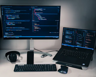 laptop computer beside monitor with keyboard and mouse