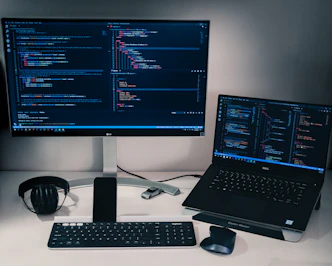 laptop computer beside monitor with keyboard and mouse