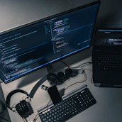 A modern desk setup featuring multiple screens displaying tech product images and review drafts.