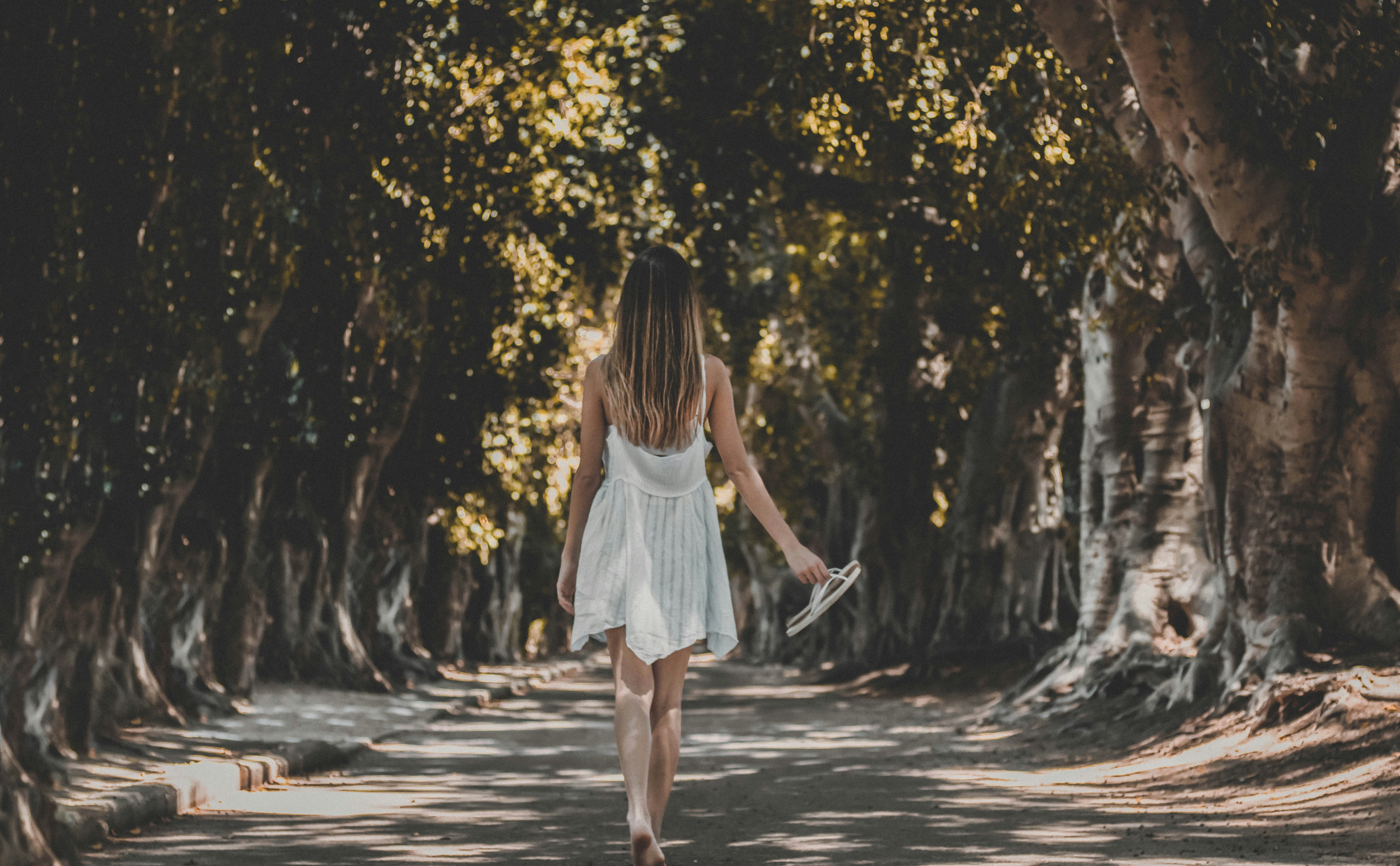 woman walking under trees