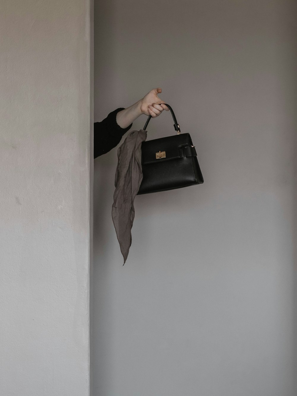 person holding black leather handbag