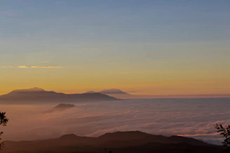 A serene mountain landscape at dawn with soft teal and deep blue hues blending into the sky.