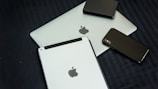 A collection of modern electronic devices, including a laptop, tablet, smartphone, and a portable external hard drive, all displaying a sleek and minimalist design with a focus on metallic and dark tones.