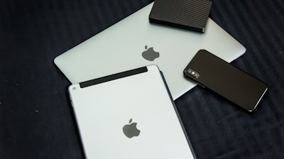 A collection of modern electronic devices, including a laptop, tablet, smartphone, and a portable external hard drive, all displaying a sleek and minimalist design with a focus on metallic and dark tones.