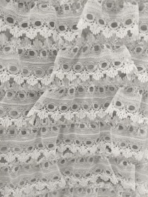 Intricate geometric lace with bold black thread on white fabric.