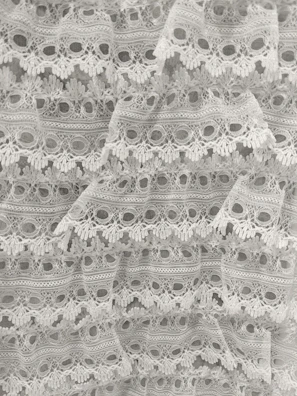Bridal lace fabric with delicate scalloped edges and floral details.