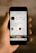 A hand is holding a smartphone displaying an Instagram profile. The profile belongs to a user named jakobowens, featuring a circular profile picture, user stats, and several icons for various Instagram functions. The screen shows text denoting the number of posts, followers, and following, along with buttons for promoting and editing the profile. Below the profile information are icons for IGTV, highlights, and YouTube, among others. The background is blurred, focusing attention on the phone and its screen.