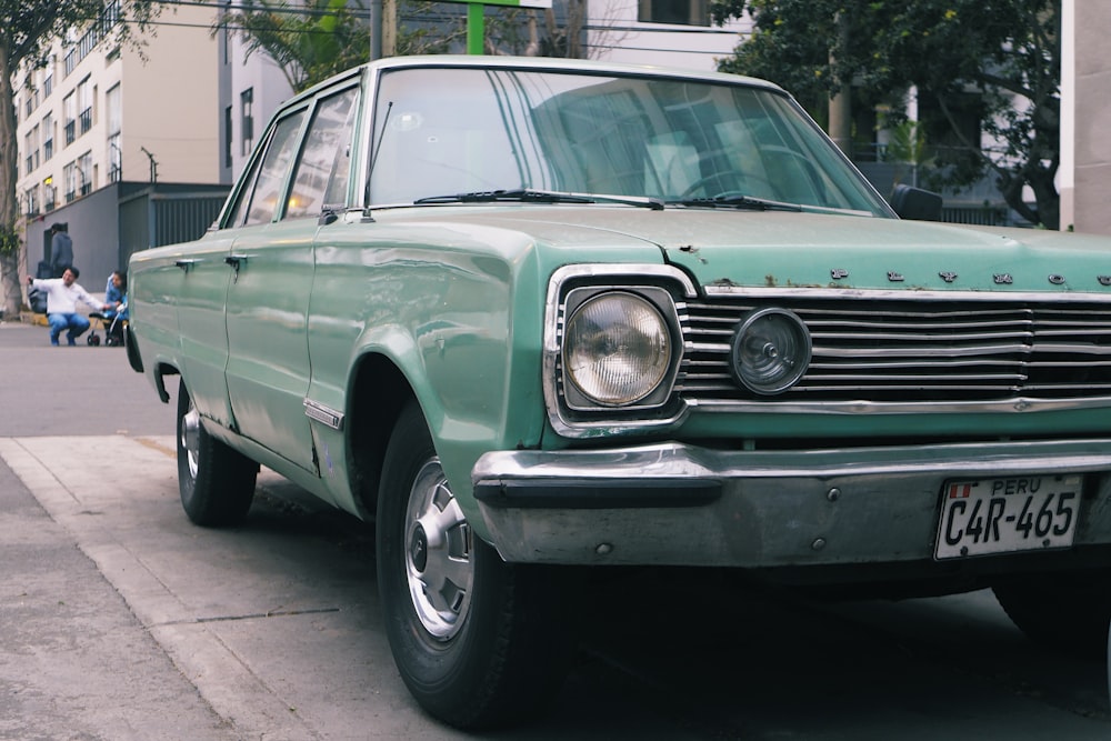 closeup photo of green sedan parked beside tree taken at daytime