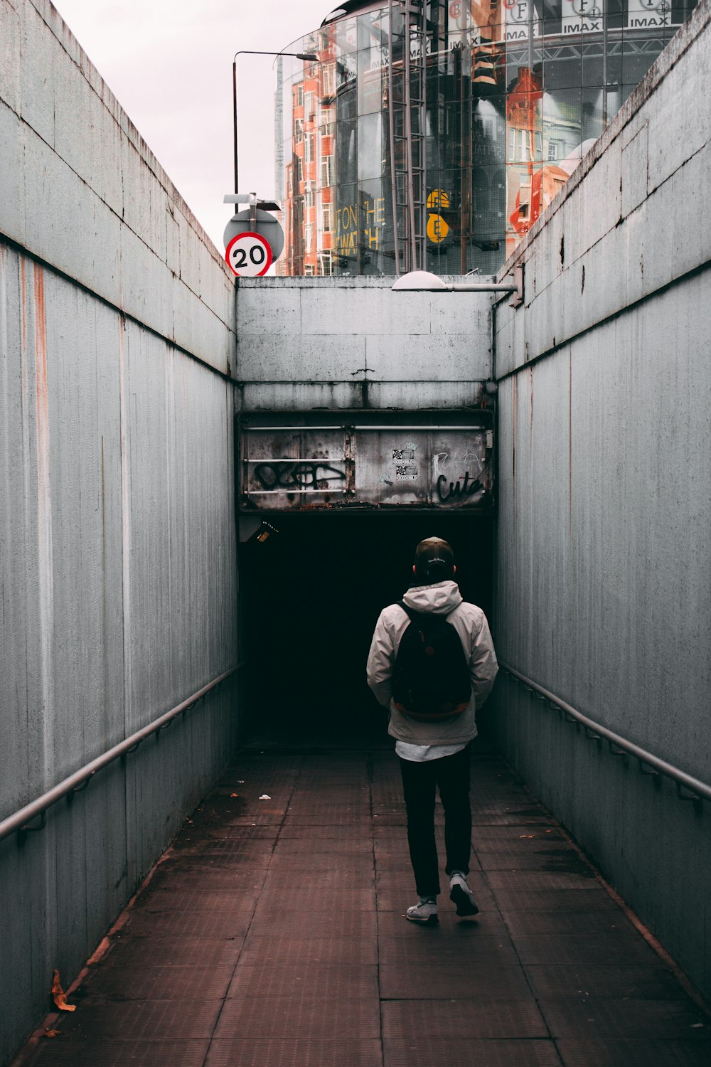 person walking near gray walls